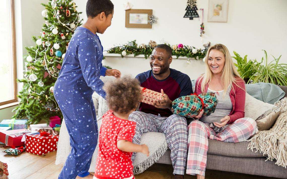 family with two young children opening christmas presents