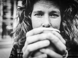 Homeless woman holding a cup of coffee